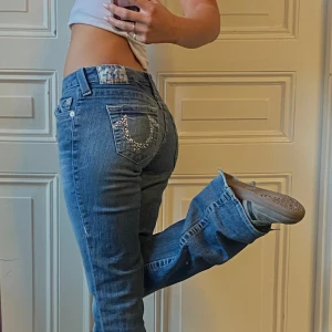 True religion med rhinestones - Skit snygga true religion jeans med rhinestones på bakfickorna. Modellen är ”boot cut”.  Storlek 27 med innerbenslängd 87 cm. Bra skick, enbart viss slitage längst ner på baksida av byxbenen (se bild). Skriv för mer information! 💗💗