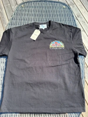 Casablanca  - Snygg svart t-shirt från Casablanca med färgglatt tryck och logga på bröstet. Klassisk rund hals och korta ärmar. Tillverkad i mjuk bomull som känns skön mot huden. Perfekt för dig som vill ha en stilren men ändå unik look.
