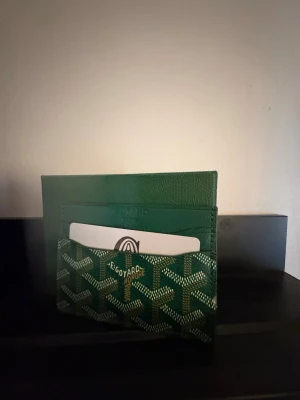 Korthållare - Snygg grön korthållare med klassiskt mönster i vitt och gult. Tillverkad i läder med flera fack för kort. Perfekt för dig som vill ha en stilren och exklusiv accessoar i fickan.