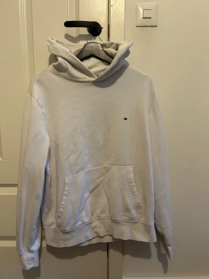 Vit hoodie från Tommy hilfiger  - Säljer denna stilrena hoodien ifrån Tommy Hilfiger. Den sitter M och är vit. Den har inga difekter på sig. Skriv till mig om funderingar och pris!!