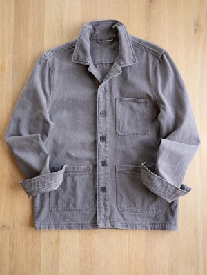 Washed Brown Chore Jacket med fickor - Stilren grå overshirt i kraftigt bomullstyg med tre stora utanpåliggande fickor och knäppning framtill. Klassisk krage och uppvikta ärmslut ger en avslappnad look. Perfekt lager på lager-plagg för dig som gillar enkel och tidlös stil.