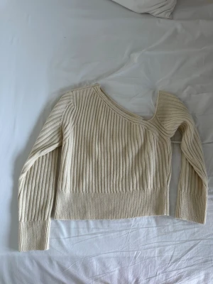 Topp med asymmetrisk ringning  - Snygg finstickad topp med asymmetrisk ringning, nyskick 