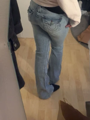 Ljusblå bootcut jeans från True religion  - Snygga ljusblå jeans med bootcut-modell och broderade detaljer på bakfickorna. Jeansen har klassisk femficksdesign och är tillverkade i denim med lätt tvättad look. Perfekta för en avslappnad och trendig stil. Ny pris 1299kr