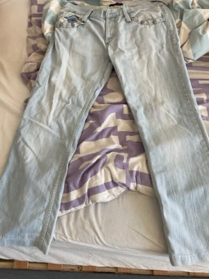 Ljusblå raka jeans med nitar,DG =Dolcer &Gabbana - Säljer ett par ljusblå jeans med raka ben och coola nitar vid fickorna. Jeansen har klassisk femficksmodell och bälteshällor. Perfekta för dig som gillar en avslappnad men ändå trendig stil.