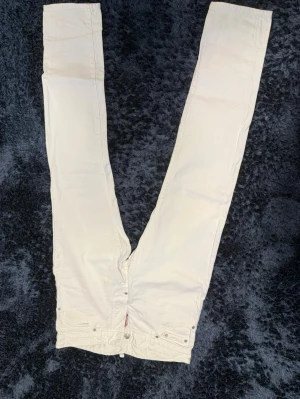 Vita jeans från Dsquared2 - Snygga vita jeans från Dsquared2 med raka ben och klassisk femficksdesign. Jeansen har en stilren look med patch på baksidan i midjan och silverfärgade nitar. Perfekta för dig som vill sticka ut med en fräsch och modern stil.