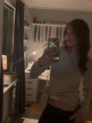 Beige långärmad topp med knyt - Trendig beige långärmad topp med knyt i sidan. Toppen har en enkel och stilren design som passar perfekt till jeans eller kjol. Tillverkad i mjukt material för en bekväm känsla och har en normal passform.