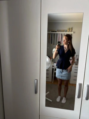 Mörkblå omlottopp med v-ringning från shein - Säljer en mörkblå omlottopp med v-ringning och korta ärmar. Toppen har en markerad midja och ett lätt utsvängd fall nedtill, vilket ger en feminin siluett. Perfekt att styla med kjol eller jeans för en trendig look.