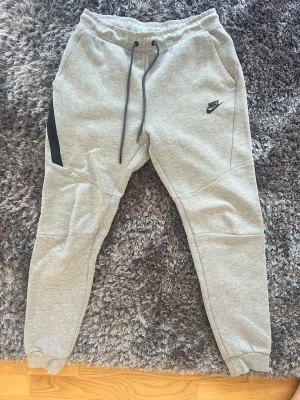 Nike tech träningsbyxor - Ett par Nike tech träningsbyxor. Saknar det svarta skyddet på ett av snörena, annars är byxorna i gott skick. Strl S.