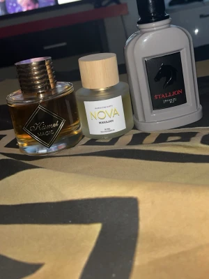 Tre parfymer: Kismet Magic, Nova, Stallion - Säljer tre olika parfymer: Kismet Magic i rund glasflaska med gulddetaljer, Nova Mahajan i frostat glas med trälock och Stallion i grå, rektangulär flaska med svart hästlogga. Alla flaskor har unik design och passar dig som gillar att variera doft.
