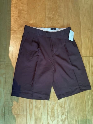 Bruna shorts från H&M - Säljer ett par helt oanvända bruna kostymshorts från hm! Storlek 48