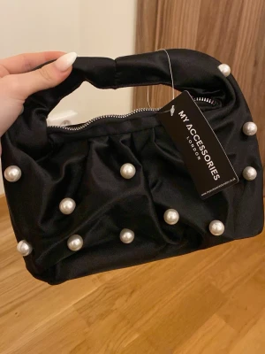 Svart pärlprydd handväska - Köpt från Asos. Aldrig använd. Svart insida. Silverdragkedja.🤍🩶🖤