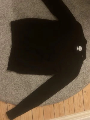 Svart tröja från These Glory Days - Snygg svart tröja från These Glory Days med rund halsringning och långa ärmar. Enkel och stilren design som passar perfekt till jeans eller chinos. Tillverkad i mjukt material för en bekväm känsla. Storlek M men har krymt.