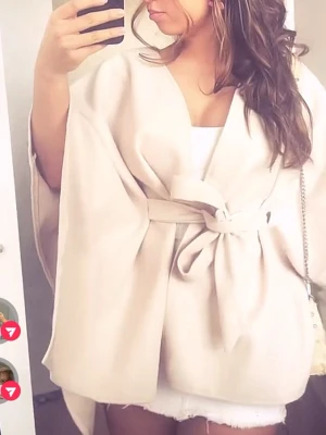 Beige poncho jacket - Snygg beige cape-rock med vid passform och knytskärp i midjan. Rocken har öppen front och faller snyggt över axlarna. Perfekt för lager-på-lager och ger en chill men ändå stilren vibe. Materialet ser ut att vara mjukt och lite tjockare tyg.