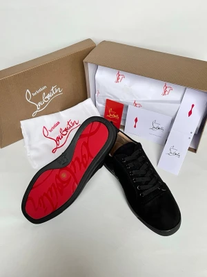 Svarta sneakers från Christian Louboutin - Snygga svarta sneakers från Christian Louboutin i mocka med klassisk röd sula. Skorna har svarta skosnören, diskret design och lågt skaft. Perfekta för dig som vill ha en exklusiv och stilren look med den ikoniska röda sulan.