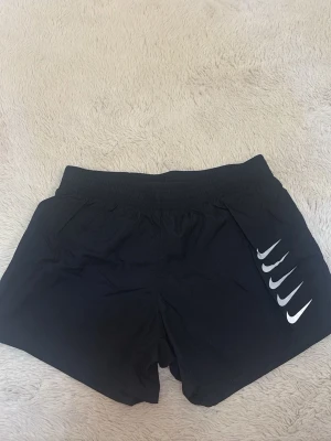 Svarta träningsshorts från Nike - Svarta träningsshorts från Nike. Shortsen har elastisk midja och är tillverkade i ett lätt och snabbtorkande material, perfekta för sport och träning. 💗