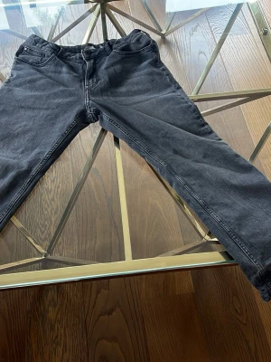 Svarta relaxed fit jeans från H&M fodrad - Säljer ett par svarta jeans från H&M med relaxed fit och justerbar midja. Jeansen har klassisk femficksdesign och är fodrade på insidan för extra komfort. Perfekta för en avslappnad och stilren look.