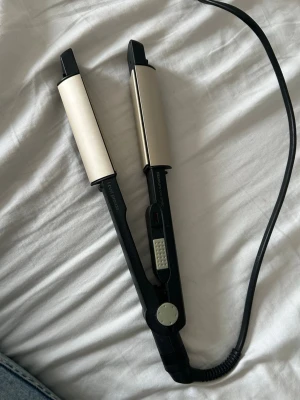 BaByliss locktång svart och beige - Säljer en locktång från BaByliss i svart och beige med rundade keramiska plattor. Perfekt för att skapa snygga lockar eller vågor. Sladd med roterande fäste för smidig användning. Enkel att justera värmen med reglaget på handtaget.