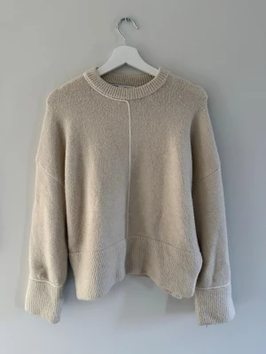 Beige stickad tröja från Zara - Säljer en beige stickad tröja från Zara med rund halsringning och markerad söm framtill. Bra skick och i storlek s men passar både xs och m