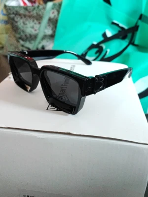 Svarta kantiga solglasögon - Säljer ett par svarta solglasögon med breda bågar och kantig form. Glasen är mörka och bågarna har en chunky design som ger en cool och trendig look. Perfekta för dig som vill sticka ut och addera edge till din outfit.