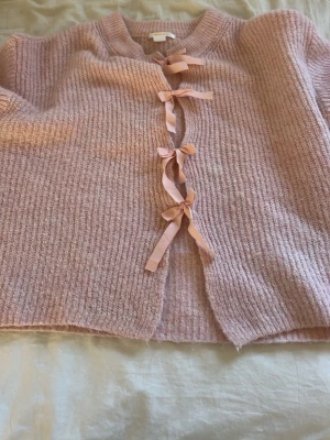 Rosa stickad kofta med rosetter - Supersöt rosa stickad kofta från Gina Tricot. Storlek 170 men passar mig som brukar ha 158/164