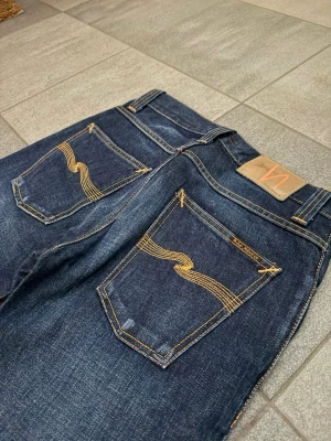 Nudie Jeans - Snygga mörkblå jeans från Nudie Jeans i modellen grim tim.  Riktigt snygga slitningar. Stolek 28/32, mycket bra skick.