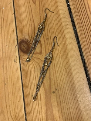 Vackra örhängen - Vackra glittriga hängande örhängen i guldaktig metall med stenar i samma färg.