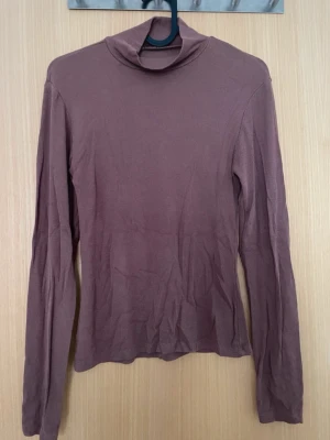 Ljusbrun ribbad turtle neck  - En enkel och stilren ljusbrun turtle neck med lång ärm och ribbad struktur. Toppen har en tight passform och är perfekt att styla med jeans eller kjol. Materialet känns mjukt och stretchigt, vilket gör den bekväm att bära hela dagen.
