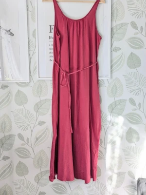 Rosa Maxiklänning Indiska Storlek S-M  - -Superskön mjuk luftig och elastisk klänninj i fint skick.  - Storlek S men passar även M.  - Använd en handfull gånger men lite avändning kan synas i tyget tyget+ kanter där det är ljusare i färg luddljusnad det finns även en mörk fläck nästan längst ned på klänningen samt har öglan till midjesnöret släppt i ena änden , se extrabilderna.  - Exakta färgen är lite svår att få på bild den är typ liknande fuschiarosa.  - Jag kan ha missat någon miniskavank men jag har försökt att granska så gott de