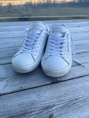 Vita låga sneakers från Philippe Model - Snygga vita sneakers från Philippe Model med klassisk låg profil och vita skosnören. Skorna har diskret logga på sidan och tungan, samt detaljer i vitt läder. Perfekta för en clean och stilren look. Använd 2 gånger. 