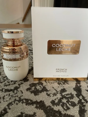 French Avenue Coconut Leche parfym - Lyxig parfym från French Avenue med doften Coconut Leche. Flaskan är vit med detaljer i guld och har en elegant, rund form. Kommer i en snygg vit och guld kartong. Innehåller 80 ml Eau de Parfum och tillverkas av Fragrance World Perfumes. Endast testad!