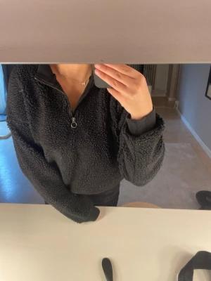 Svart teddytröja med halv dragkedja - Mysig svart teddytröja med halv dragkedja. Tröjan har en oversized passform och ribbade muddar vid ärmslut och nederkant. Den är ifrån LMTD i storlek S!!