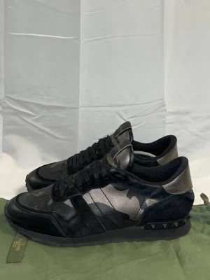 Valentino svarta camo sneakers - Säljer ett par riktigt schyssta rockrunners i storlek 43. Man får med dustbag inte box! I ok skick Skriv vid minsta fundering 