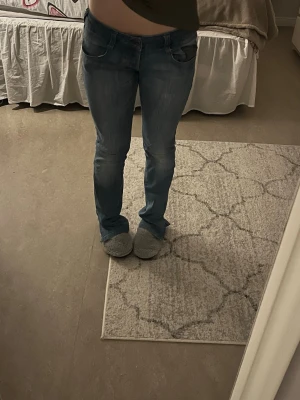 Blå  jeans med dragkedjedetalj - Säljer ett par blå raka jeans med snygg tvätt och dragkedjedetalj på bakfickan. Jeansen har klassisk femficksdesign och normal midja. Perfekta för dig som gillar en avslappnad men ändå trendig look. Liten defekt (sista bilden) går lätt att sy. (egensydd slitt vid benen)