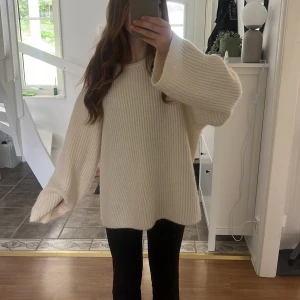  vit stickad tröja med en vit silkes rosett - Supermysig  stickad tröja i creme vit med öppen rygg. Snygg detalj med stor rosett i nacken. Ribbstickad struktur och mjukt material. Bara andvänt tröjan 2 gånger! Den är i storlek L men funkar även för M