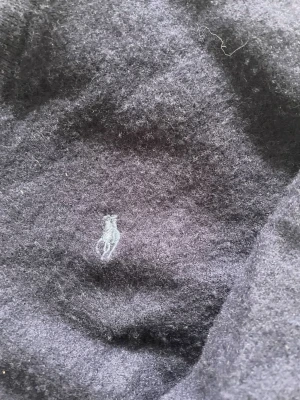 Mörkblå stickad tröja Polo Ralph Lauren - Mörkblå stickad tröja från Polo Ralph Lauren med V-ringning och den klassiska broderade loggan på bröstet. Tröjan har långa ärmar och är gjord i mjukt material, perfekt för lager på lager och en stilren look. (Äkta)