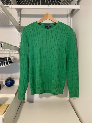 Grön kabelstickad tröja Polo Ralph Lauren - Säljer denna gröna kabelstickade tröja från Ralph Lauren i ett sjukt bra skick! Barnstorlek L vilket motsvarar herr XS. Kontakta vid funderingar och kom gärna med prisförslag!