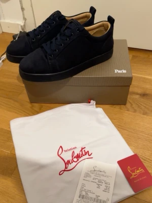 Christian Louboutin - Snygga mörkblå sneakers från Christian Louboutin i mocka med klassisk låg siluett. Skorna har svarta snören, svart sula och beige innersida. Perfekta för dig som gillar exklusiva och stilrena sneakers med lyxig känsla.