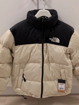 The North Face Retro Nuptse Dunjacka S(Helt Oanvänd!) - Helt oanvänd med tagg kvar i färgen Gravel och storlek S. Köpt från Zalando  med. Kvittot skickas även med.