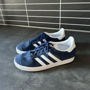 Blå Adidas Gazelle - Jag säljer mina adidas gazelle då dem tyvärr är för stora för mig. Köpte dem begangnat använda några få gånger. Och har använt dem ett par antal gånger nu. Pris kan diskuteras! Hör gärna av er för frågor eller fler bilder😊