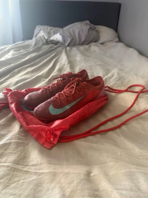 Nike Mercurial röda fotbollsskor - Nike mercurial vapor 16 i färgen rosa/röd med ljusblå detaljer i ett bra skicka trotts andvänding med defekter på sulan så funkar dom utmärkt.ny pris cirka 3000. Hör av er vid frågor om pris eller annat😁