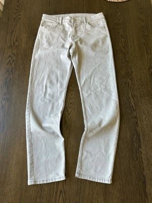 Beige raka jeans i klassisk modell - Snygga beige jeans med rak passform och fem fickor. Jeansen har en klassisk midja och stängs med knapp och dragkedja. Perfekta för en clean och stilren look. Materialet är denim i bomull. Passar dig som gillar minimalistisk stil.