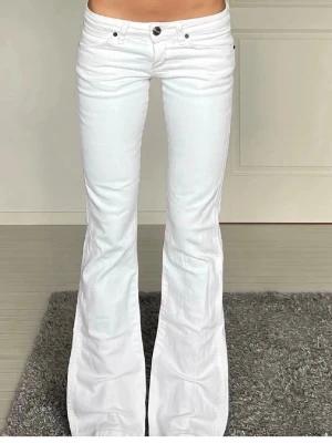 Vita bootcut jeans från Wrangler - Snygga vita bootcut jeans från Wrangler med klassisk femficksdesign och logotyp på bakfickan. Jeansen har låg midja och utsvängda ben, perfekta för en trendig look. Tillverkade i stretchigt denim för skön passform. Skriv för frågor !💕