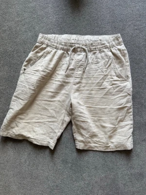 Beiga linneshorts Kappahl  - Snygga och luftiga beiga shorts i linne med elastisk midja och snörning. Perfekta för varma dagar och har både sidofickor och bakfickor för en avslappnad look. Nice till sommaren. (Pris kan diskuteras)