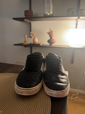 Valentino flycrews - Snygga sneakers i svart läder med vita detaljer på sidorna och vit sula. Skorna har klassisk låg profil och svarta skosnören. Perfekta för en stilren och avslappnad look.