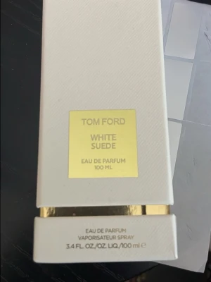 Tom Ford White Suede EdP 100ml - Tom Ford White Suede Eau de Parfum 100 ml i elegant vit och guldig flaska. Parfymen har en lyxig och stilren design med en rektangulär form och exklusiv känsla. Perfekt för dig som gillar exklusiva dofter och snygg förpackning.