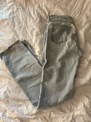 Ljusblå low waist straight jeans - Säljer ett par ljusblå jeans med low waist och raka ben. Modellen är straight och byxorna har klassiska fem fickor. Midjemått 24 och längd 34. Perfekta för en avslappnad och trendig look.