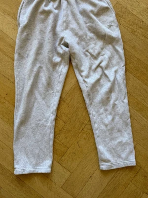 Ljusgrå mjukisbyxor Kook N Keech - Ljusgrå mjukisbyxor från Kook N Keech med elastisk midja och avslappnad passform. Tillverkade i mjukt bomullsmaterial, perfekta för chill dagar. Diskret logga på höften och raka ben.