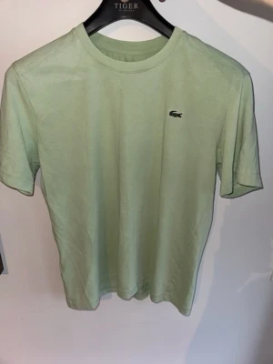 Ljusgrön Lacoste Sport t-shirt - Fräsch mint grön t-shirt från Lacoste Sport med klassisk krokodillogga på bröstet. T-shirten har rund halsringning och korta ärmar, tillverkad i mjuk bomull.