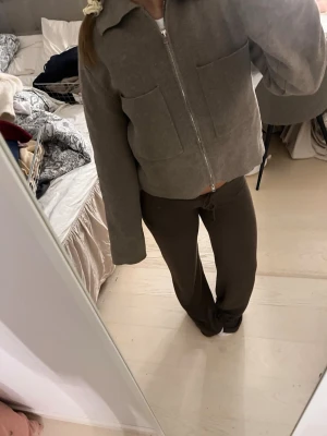 Beige ziptröja med stora fickor - Beige ziptröja med krage och två stora fyrkantiga fickor framtill. Tröjan har en rak, avslappnad passform och långa ärmar. Tillverkad i mjukt material som ger en chill och clean look.