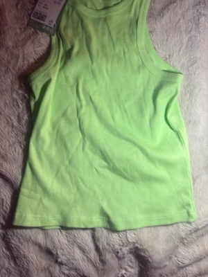 Ljusgrön ribbad linnetopp - Snygg ljusgrön ribbad linnetopp med ärmlös design och rund halsringning. Perfekt för en fräsch och sportig look. Mjuk och stretchig bomullskvalitet som sitter skönt på kroppen.